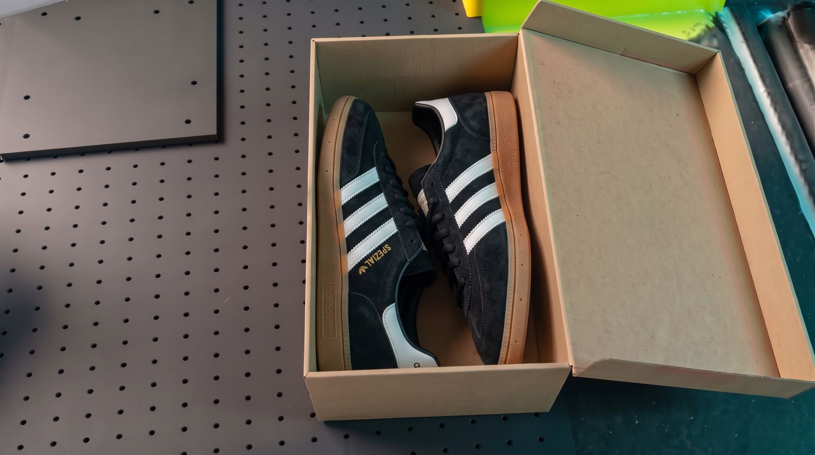 La caja abierta con zapatillas de ante negro